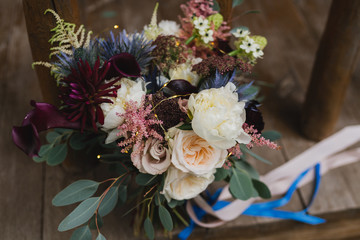 Beautiful modern bridal bouquet of colorful fresh flowers with sikl ribbons. Classic wedding traditional accessory.