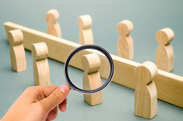 Wooden figures of people are separated by a barrier. Social classes. Competition between teams. The...