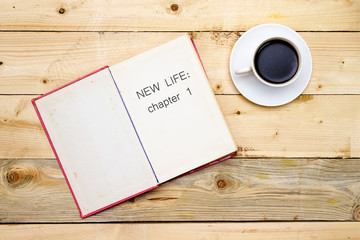 New life: chapter 1 on open book on woodne table