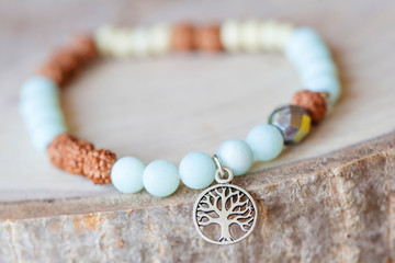 Mineral stone amazonite and tree pendant bead bracelet on natural wooden background