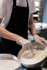 Fototapeta premium Master chef prepares a sweet dessert for the production of sweets. Mixing dough and cream for the cake in a deep bowl.