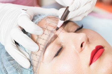Naklejka premium A young girl is carried out the correction of eyelashes in the beauty salon close-up. 