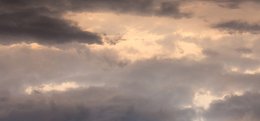 Obraz premium Dramatic dark clouds in a stormy sky during the sunset, a panorama_