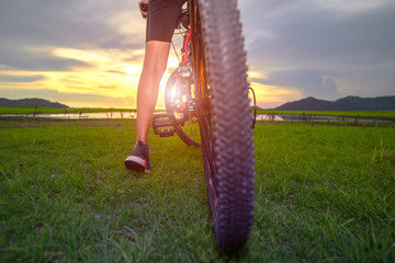 leg of woman cyclist bicycle paused riding on the way of meadow field, adventure woman riding...