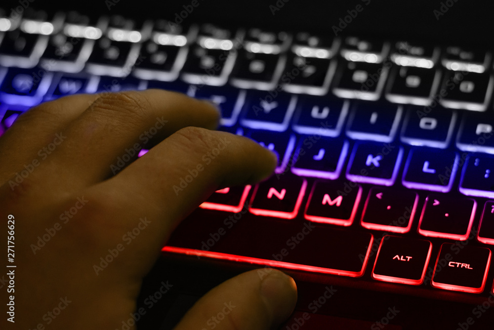 Poster man's hand typing on keyboard with white, blue and red backlight. backlight of the keyboard in color