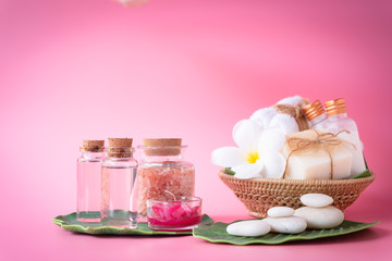 Obraz na płótnie Canvas Spa Himalayan salt,red candle,milk and rose liquid.soap,white towel,flowers ,zen stone set on green leaves over pink background