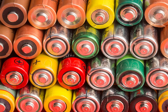 Stack of used batteries on a red background. Background of alkaline battery AA size