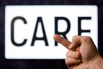 Male showing middle finger to the screen with inscription CARE. Symbol of carelessness