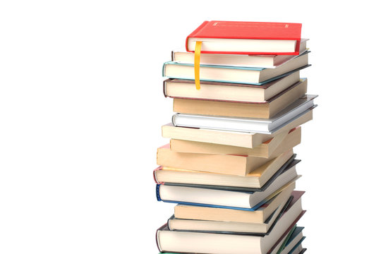 High pile of different books isolated on a white background. Red book with yellow bookmark on top of the pile