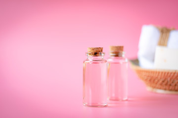 Spa wellness with rose oil bottle,milk soap,white towel in wooden tray on pink background