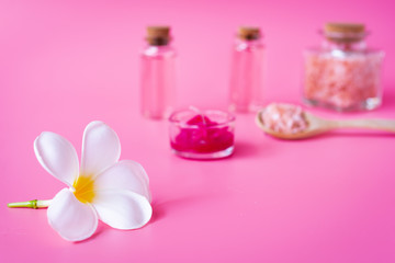 Spa wellness concept,white plumeria flower ,red candle,sea salt  and rose liquid soap bottle on pink background