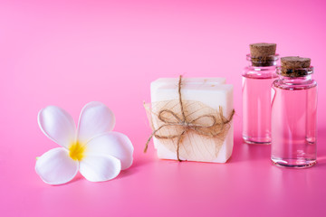 Obraz na płótnie Canvas Spa wellness with milk soap,rose oil bottle and beautiful white plumeria flower on pink background