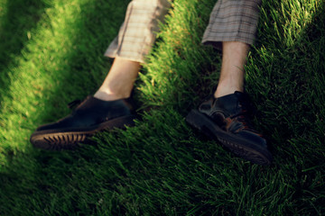 Man lying and relaxing on the grass. Legs, top view.  Pair of male legs in shoes lying on green grass. Very fashionable shoes. Photo for shoe store. Sale.