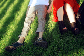 Couple lying and relaxing on the grass. Legs, top view. two pair of male and female legs in shoes lying on green grass. Very fashionable shoes. Photo for shoe store. Sale.