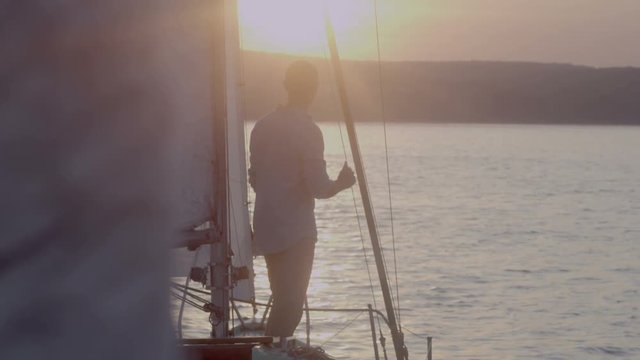 Young man stands on a yacht in the morning looking into the distance