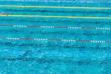 Red and white swimming lanes in beautiful blue water, empty outdoor swimming pool, summer sunny day, copy space, aerial view