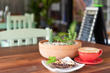 Red hot coffee cup and bakery on wood table at outdoor restaurant