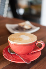 Red hot coffee cup and bakery on wood table in restaurant