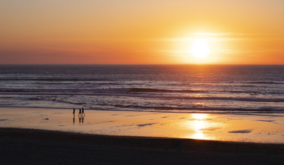 Friends walking on the beach at sunset, San Sebastian