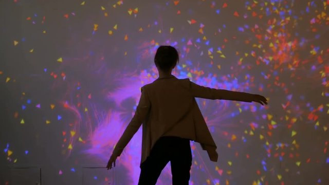 Large screen augmented reality experience - woman waving her arms in front of display. Science, future and technology concept