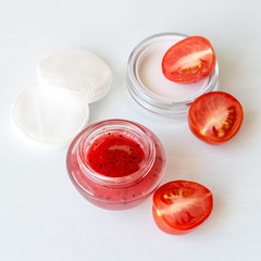 A small round  jar with a cosmetic face mask based on tomatoes on a light background. Selective focus.