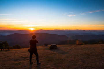 Fototapeta na wymiar Beautiful mountain range in sunset and orange sky with one man look at view.