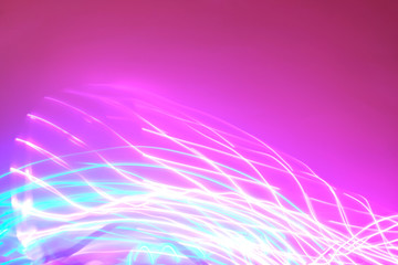 Abstract background of neon lights in motion on pink backdrop. Place for your design.
