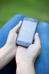 Broken glass screen smartphone in hand.Hand holding mobile phone with broken screen. Smartphone with cracked display in hand.Hand hold the cellular.