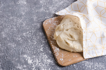 Closeup of dough under the napkin on the wooden board.Process of rising dough, empty space for your design