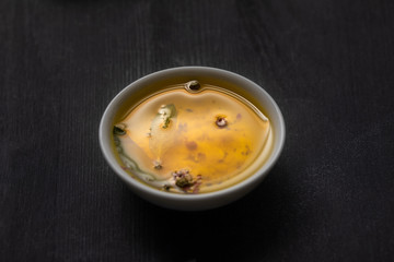 aromatic oil in bowl with spices and herbs on wooden black table