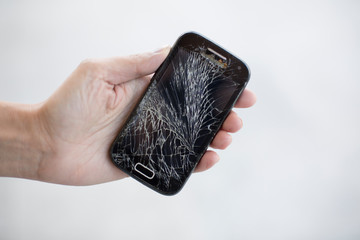 Broken glass screen smartphone in hand.Hand holding mobile phone with broken screen. Smartphone with cracked display in hand.Hand hold the cellular.