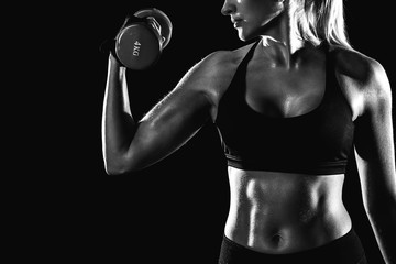 Black and white photo of a girl swinging her biceps with a dumbbell.