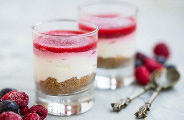 Cheesecake desserts in glasses, fresh red berries topping gelly, cream cheese and digestive biscuits desserts in transparent glasses