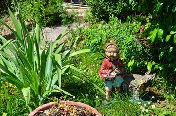 vintage garden figurine standing in the middle of bushes