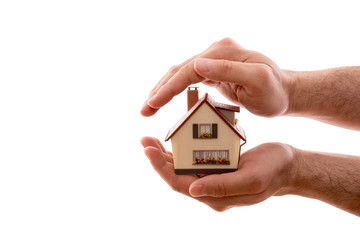 Home protection. Small house covered by hands isolated on white background with clipping path 