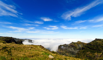 Fototapeta na wymiar Wide angle shot of Mountain peaks against blue sky with white clouds on a beautiful summer day. Near Pico de Areeiro (Arieiro), Central Madeira, Portugal, Europ