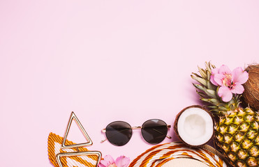 Vacation female stuff, summer flat lay: straw hat, sun glasses, sunscreen cream, tropical fruits on pink background. Copyspace for text. top view, flat lay