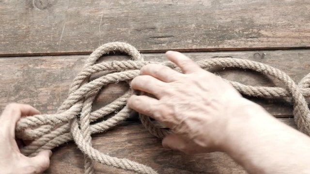 man undoing the knot in a rope,