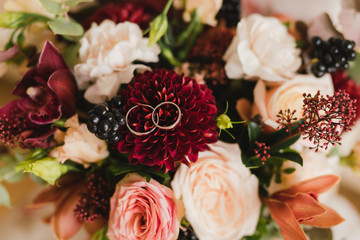 Modern wedding jewelry. Closeup of two wedding rings on natural background with flowers and leaves.