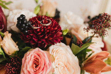 Modern wedding jewelry. Closeup of two wedding rings on natural background with flowers and leaves.