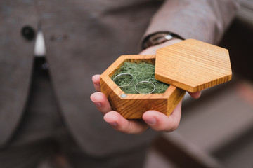 Fototapeta premium Modern wedding jewelry. Closeup of a caucasian man holding two wedding rings in a vintage box in his hands.