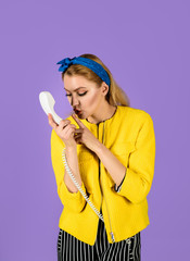 Woman talking at retro handset. Woman holds telephone tube. Pinup girl in jacket talking by telephone. Woman holds phone handset making quiet gesture. Girl holds handset and shows silence gesture. Shh