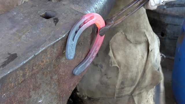 Schmiedearbeit, ein Hufeisen wird auf einem Amboss bearbeitet (geschlagen)