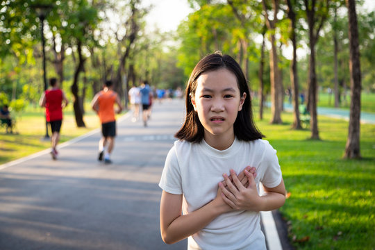 Communicates the symptoms of heart disease,immediately,Asian little girl with chest pain suffering from heart attack after run,exercise in outdoor park,child with certain symptoms,difficulty breathing