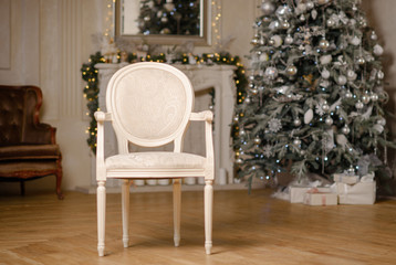 Classic Christmas decorated interior room New year tree. Christmas tree with gold decorations. Modern white classical style interior design apartment with fireplace and armchair.