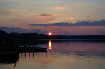 Fototapeta na wymiar Marvelous pink vivid sunset during golden hour at the lake shore near the old wharf.