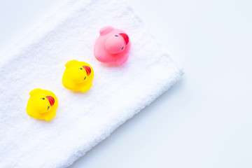 Pink and yellow duck  toys on white towel. Kids bath concept.