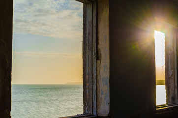 sea landscape and sun in the window of the destroyed room