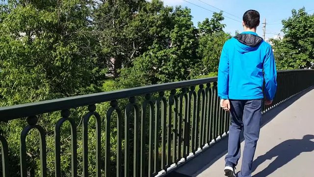 Walk men with disabilities in the city. He approaches the fence of the bridge and admires the view. Lameness, cerebral palsy