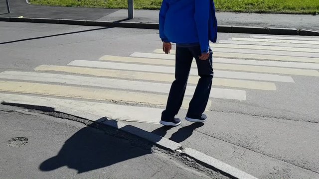Limping a grown man enters the crosswalk. Puts his feet on tiptoe - disability with cerebral palsy